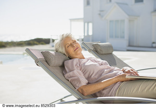 Seniorin schläft auf einem Liegestuhl am Pool
