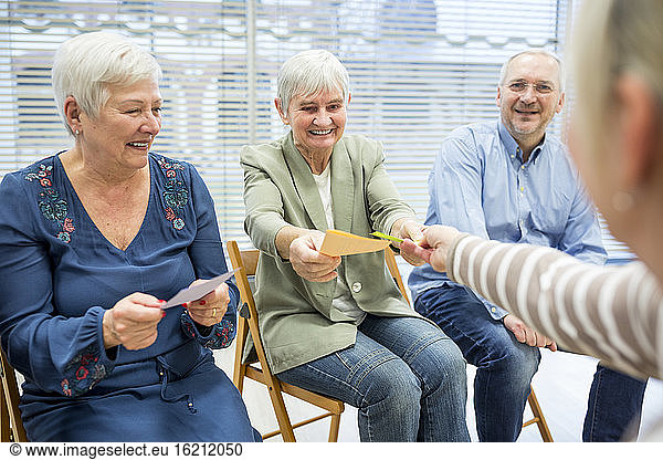 Seniors in retirement home attending group therapy using colorful paper cards