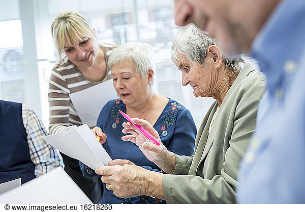 Seniors in therapy group in retirement home writing down notes on sheets of paper