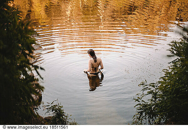 Sensual woman standing in lake in forest