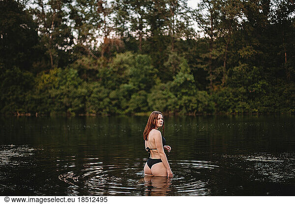 Sensual woman standing in lake in forest