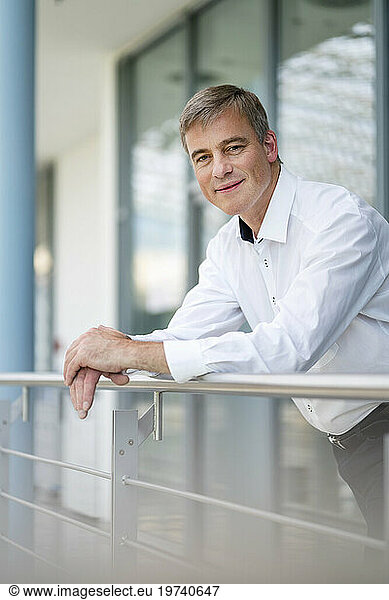 Serene businessman leaning on railing in office building