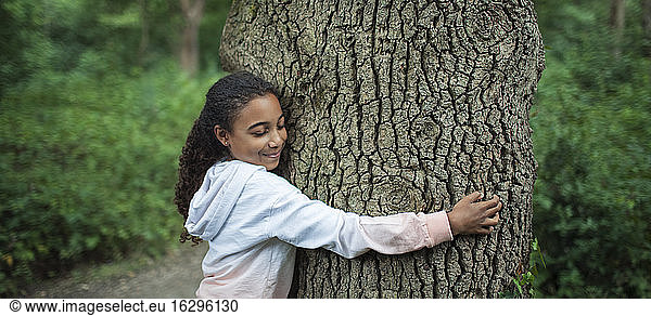 Serene girl hugging tree trunk in woods
