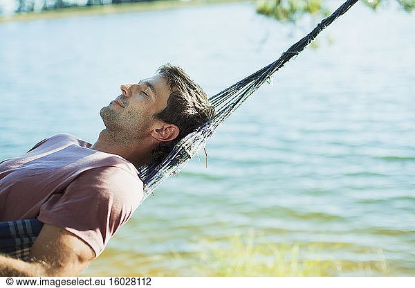 Serene man laying in hammock at lakeside