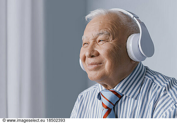 Serene senior businessman wearing headphones and listening audio