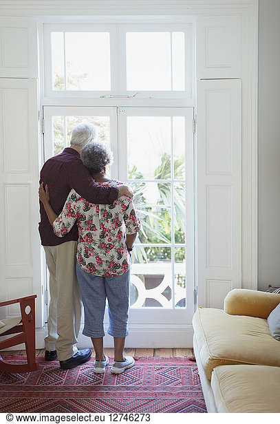 Serene senior couple looking out living room window