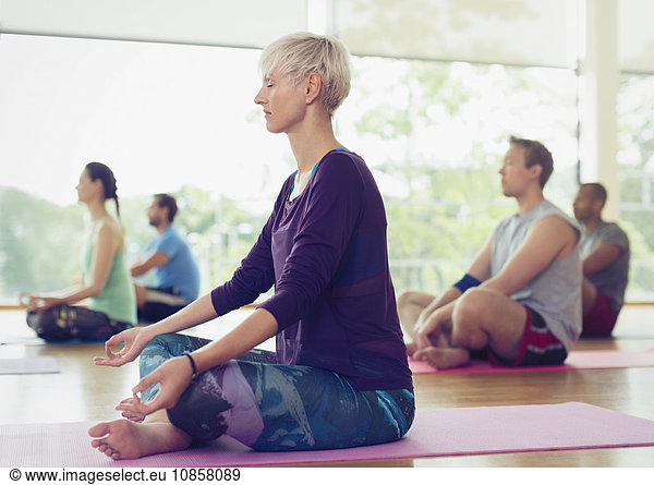 Serene woman in lotus position in yoga class