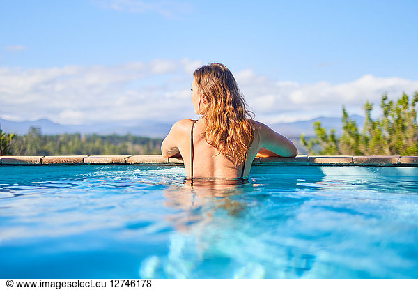 Serene woman in sunny swimming pool