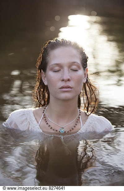 Serene woman with eyes closed in river