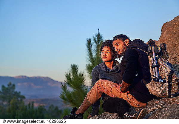 Serene young hiking couple enjoying sunset on rocks