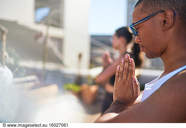 Serene young man practicing yoga on sunny patio