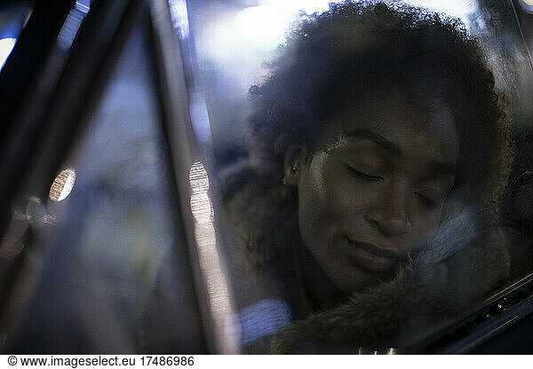 Serene young woman with eyes closed in car window