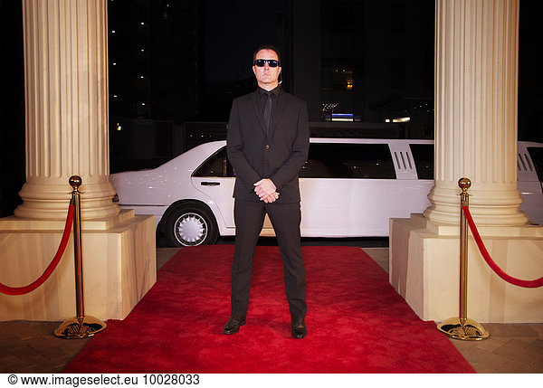 Serious bodyguard in sunglasses protecting red carpet at event
