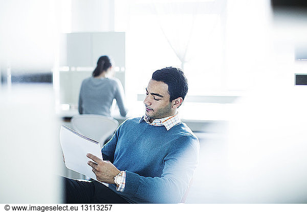 Serious businessman reading document while sitting in office