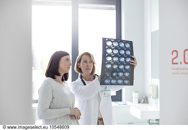 Serious doctor and patient reviewing x-rays in examination room