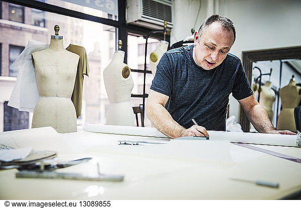 Serious fashion designer working at table in design studio