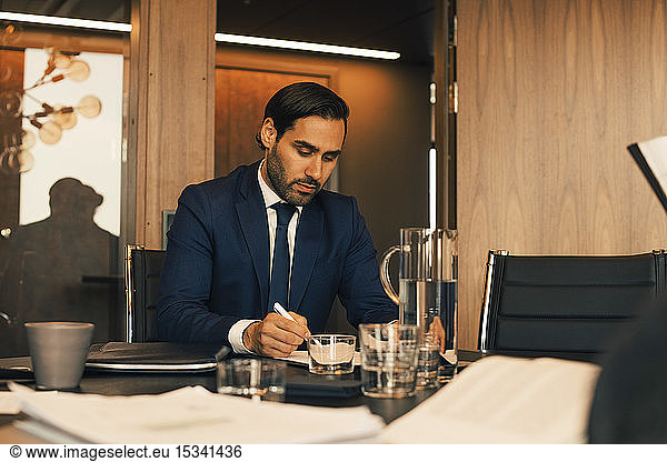 Serious male financial advisor reviewing documents at legal office