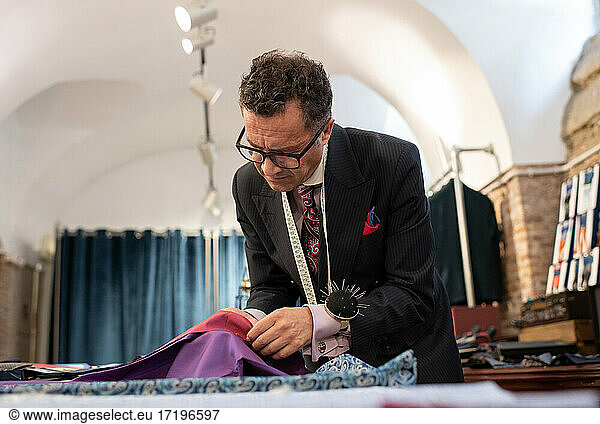 Serious male tailor selecting material