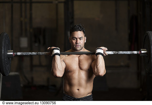 Serious man lifting barbells at gym