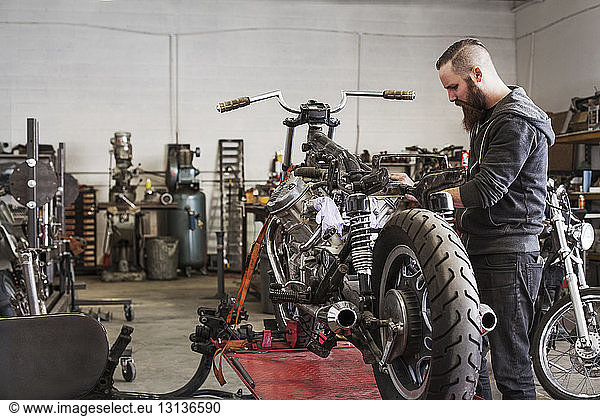 Serious mechanic working on motorcycle at repair shop