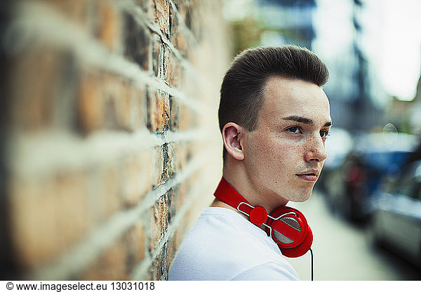 Serious teenage boy with headphones looking away
