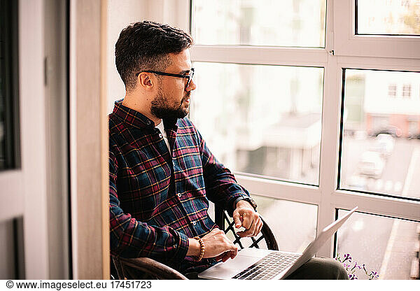 Serious thoughtful man using laptop computer at home