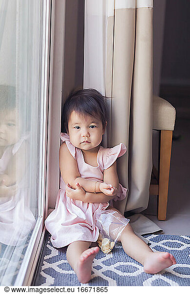 Serious toddler sitting by the door and looking at camera