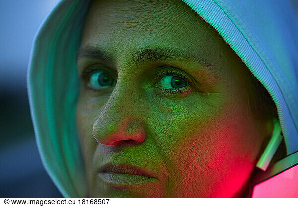 Serious woman wearing hood with reflection of lights on face