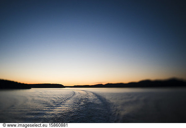 Setting Sun Behind Islands With Water and Ferry Wake