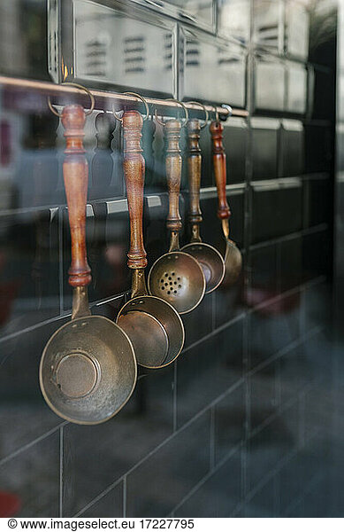 Several kitchen utensils hanging on a wall seen through glass in restaurant