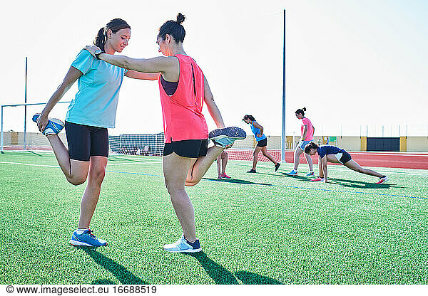 several young women practice stretching after training