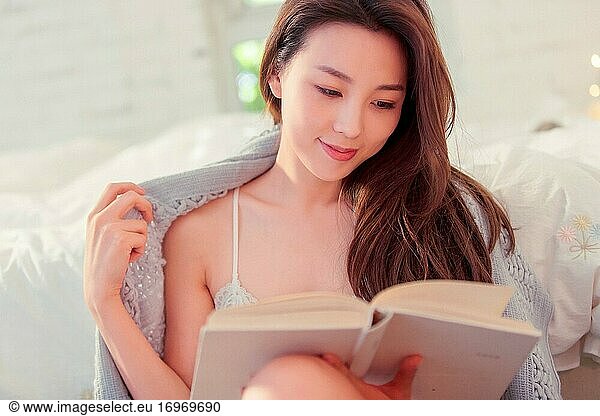 Sexy junge Frau sitzt auf dem Boden und liest ein Buch