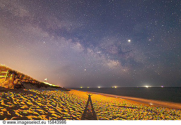 Shadow of a man in the beach sand under the Milky Way galaxy.