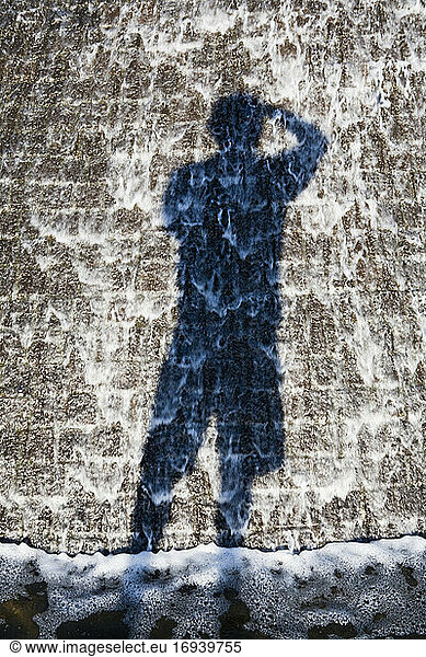 Shadow of an adult against a mottled concrete surface