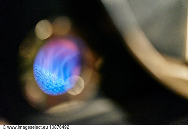 Shallow focus close up of blue gas flame roasting coffee in coffee shop