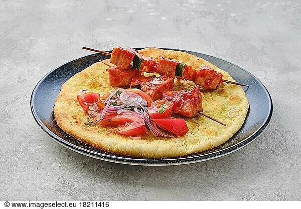 Shashlik served on tortilla with tomato and red onion