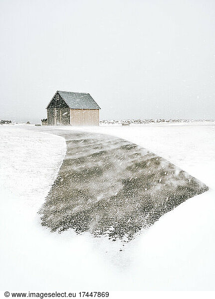 Shed in snowy field with path in countryside