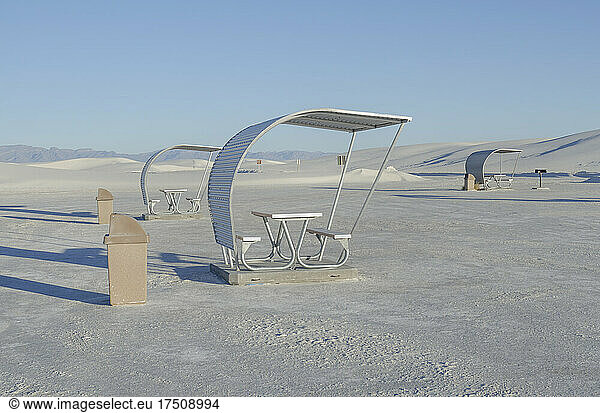 Shelters and trash bins among gleaming white sand dunes.