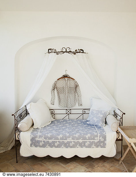 Shirt hanging over day bed with canopy on patio