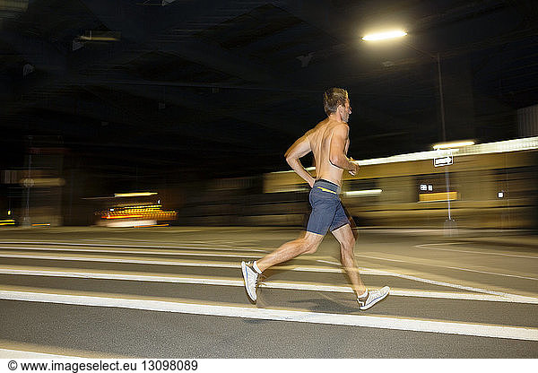 Shirtless athlete running on street at night