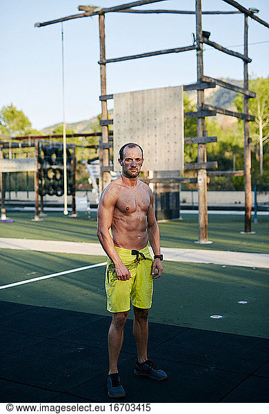 Shirtless fit young man posing at outdoors gym military camp