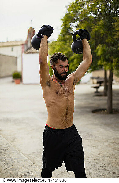 Shirtless guy training with kettlebell on the street