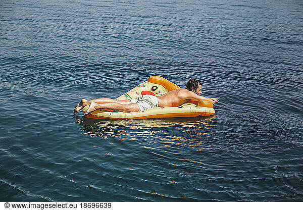Shirtless man floating on sea at vacation