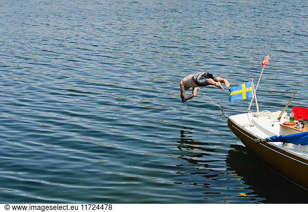 Shirtless man jumping into sea