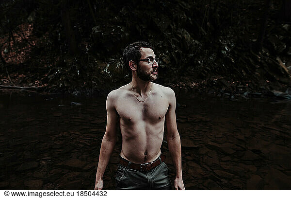 shirtless man wading in cold creek