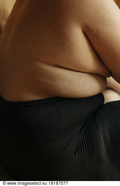 Shirtless woman with stretch marks wearing black underwear