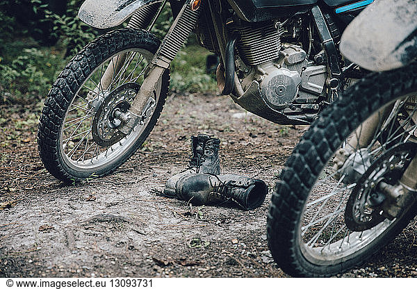 Shoes by parked motorcycles in forest