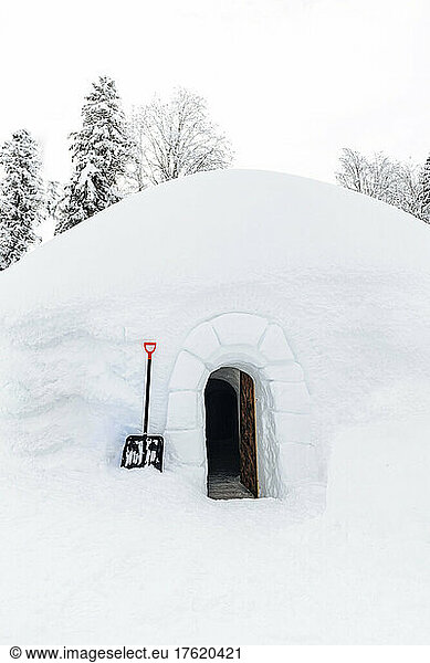 Shovel by entrance of snow covered igloo