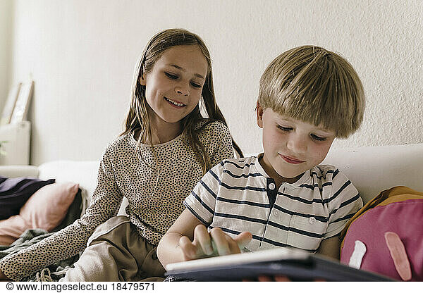 Sibling sharing tablet PC sitting at home