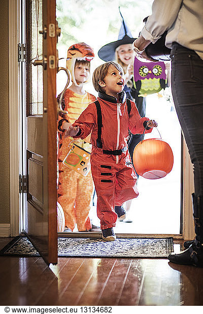 Siblings dressed for Halloween party entering house